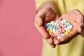 A handsome man in T-shirt on a pink background holding pills in his hand Royalty Free Stock Photo