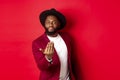 Handsome and masculine Black man asking come closer, luring to step forward, calling for you, standing over red Royalty Free Stock Photo