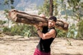 Handsome masculine man exercising in nature holding a huge log