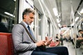 Mature businessman with smartphone in a metro train. Royalty Free Stock Photo