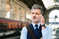 Mature businessman with smartphone on a train station. Royalty Free Stock Photo