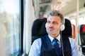 Mature businessman with headphones travelling by train. Royalty Free Stock Photo