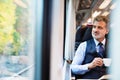 Mature businessman with coffee travelling by train. Royalty Free Stock Photo