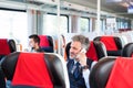 Mature businessman with smartphone travelling by train. Royalty Free Stock Photo