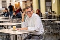 Handsome mature creative freelance businessman talking on the mobile phone and smiling while working in coffee shop urban outdoor Royalty Free Stock Photo