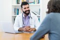 Handsome mature doctor with hipster beard talking with healthy patient