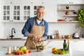 Handsome Mature Man Adding Salt To Salad While Cooking At Home Royalty Free Stock Photo