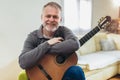 Man in casual clothes is smiling while playing guitar at home Royalty Free Stock Photo