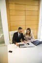 Handsome mature man with digital tablet and young woman business partners with laptop working in office Royalty Free Stock Photo