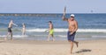 A handsome mature man hits a ball while playing matkot on the beach