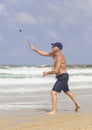 A handsome mature man hits a ball while playing matkot on the beach