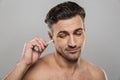 Handsome mature man holding cotton bud take care of his ears cleaning it. Royalty Free Stock Photo