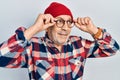 Handsome mature man holding glasses, wearing wool hat smiling looking to the side and staring away thinking Royalty Free Stock Photo