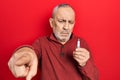 Handsome mature man holding spark plug pointing with finger to the camera and to you, confident gesture looking serious