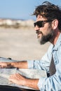 Handsome mature man outside the car using paper guide map on car hood. Bearded adult male people enjoy travel lifestyle and Royalty Free Stock Photo