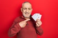 Handsome mature man playing poker holding cards smiling happy pointing with hand and finger Royalty Free Stock Photo