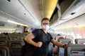 Handsome mature man in protection face mask during boarding in airplane. Safety transportation while coronavirus epidemic