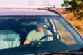 Handsome mature man sits behind the wheel in his car in nature