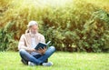 Handsome mature man sitting on green grass and reading book Royalty Free Stock Photo