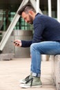 Handsome mature man sitting by the street using cellphone Royalty Free Stock Photo