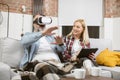 Man sitting on couch in VR headset while woman using tablet Royalty Free Stock Photo