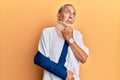 Handsome mature senior man wearing cervical collar and arm on sling with hand on chin thinking about question, pensive expression Royalty Free Stock Photo