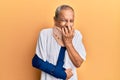 Handsome mature senior man wearing cervical collar and arm on sling laughing and embarrassed giggle covering mouth with hands, Royalty Free Stock Photo