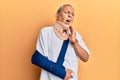 Handsome mature senior man wearing cervical collar and arm on sling touching mouth with hand with painful expression because of Royalty Free Stock Photo