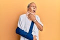 Handsome mature senior man wearing cervical collar and arm on sling touching painful neck, sore throat for flu, clod and infection Royalty Free Stock Photo