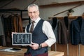 handsome mature tailor holding chalkboard with open sign Royalty Free Stock Photo