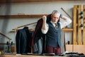 handsome mature tailor putting jacket on shoulders