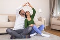 Handsome man with beautiful woman dreaming a new home. Happy married couple moves to new apartment. Happy couple making roof with Royalty Free Stock Photo