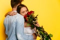 Lovely woman hugging man and sniffing red roses