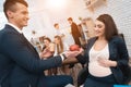 Handsome man in suit gives apple to young pregnant woman in office. Pregnancy at work.