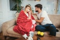 Man taking care of his sick girlfriend lying on the sofa