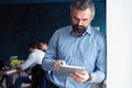 Handsome middle age businessman with digital tablet in the modren office. Royalty Free Stock Photo