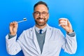 Handsome middle age dentist man holding denture and toothbrush smiling with a happy and cool smile on face Royalty Free Stock Photo