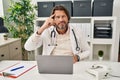 Handsome middle age doctor man working at the clinic pointing unhappy to pimple on forehead, ugly infection of blackhead Royalty Free Stock Photo