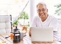 Handsome middle age hispanic man with grey hair and glasses working using computer laptop at home Royalty Free Stock Photo