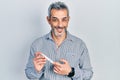 Handsome middle age man with grey hair holding glucometer device smiling with a happy and cool smile on face