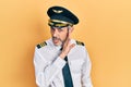 Handsome middle age man with grey hair wearing airplane pilot uniform hand on mouth telling secret rumor, whispering malicious