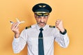 Handsome middle age man with grey hair wearing airplane pilot uniform holding toy plane annoyed and frustrated shouting with Royalty Free Stock Photo