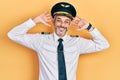 Handsome middle age man with grey hair wearing airplane pilot uniform relaxing and stretching, arms and hands behind head and neck Royalty Free Stock Photo