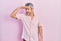 Handsome middle age man with grey hair wearing casual shirt very happy and smiling looking far away with hand over head Royalty Free Stock Photo