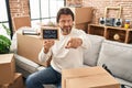 Handsome middle age man holding blackboard with new home text pointing with finger to the camera and to you, confident gesture Royalty Free Stock Photo