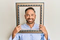 Handsome middle age man holding blank empty banner smiling with a happy and cool smile on face