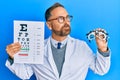 Handsome middle age man holding optometry glasses and medical exam smiling looking to the side and staring away thinking Royalty Free Stock Photo