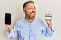 Handsome middle age man holding smartphone and credit card angry and mad screaming frustrated and furious, shouting with anger Royalty Free Stock Photo