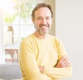 Handsome middle age man sitting on the sofa relaxed with crossed arms  and smiling at the camera at home Royalty Free Stock Photo