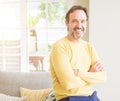 Handsome middle age man sitting on the sofa relaxed with crossed arms  and smiling at the camera at home Royalty Free Stock Photo